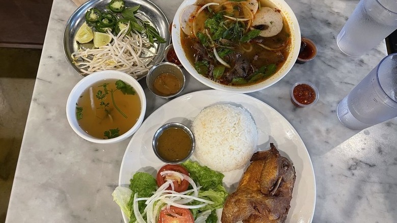 A bowl of pho, a plate of chicken, and herbs from Phở Tầu Bay
