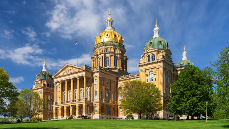 The Iowa state capital building in Des Moines with a partly cloudy sky behind it.