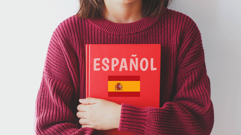 Person holding a Spanish textbook