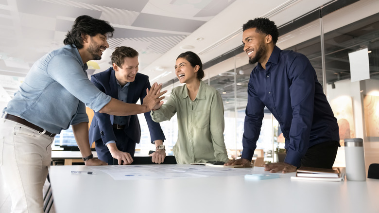 Office workers high-fiving around a conference table