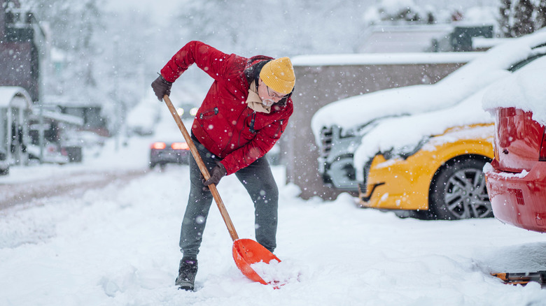 Person in winter clothes shoveling snow.