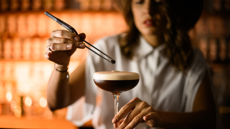 A bartender putting a coffee bean on an espresso martini