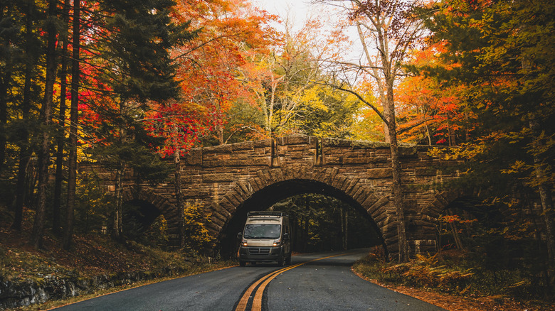 A camper van driving under stone bridge at Acadia National Park in the fall