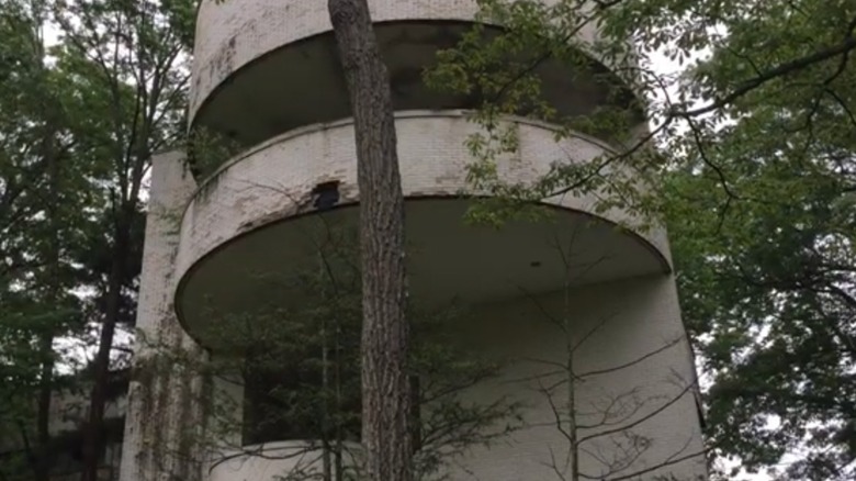 Abandoned white circular building in forest Unity House