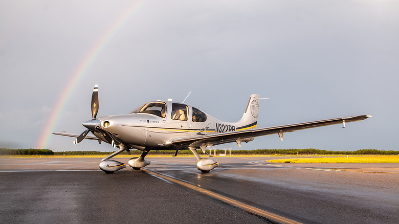 small airplane on tarmac with rainbow in background