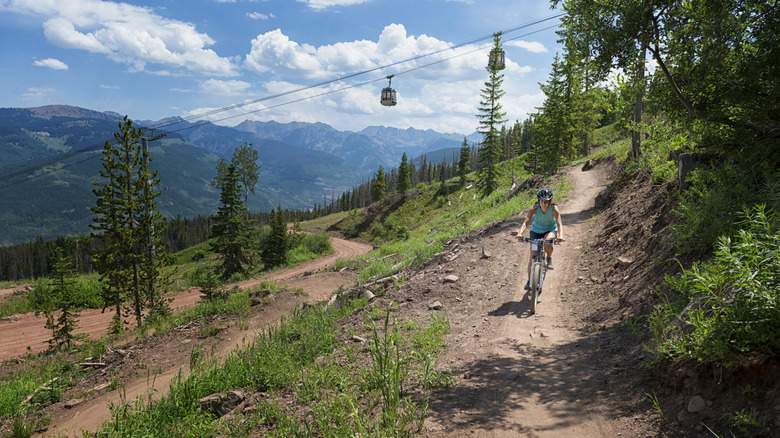 Woman bikes down trail near ski gondola