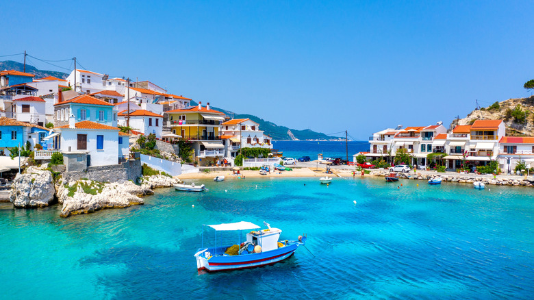 Boat in curved port with white houses red tiled roofs Samos