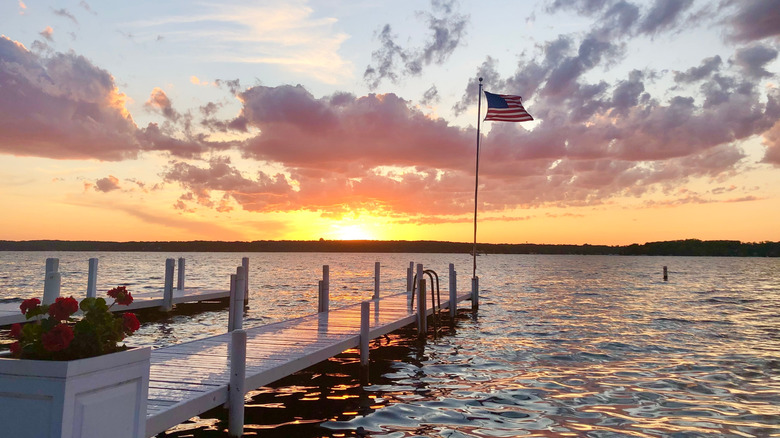 A sunset over lake geneva with an American flag perched at the end of a dock