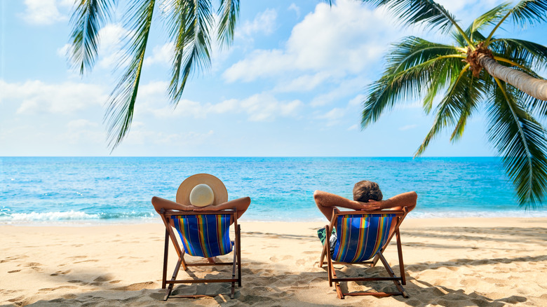 Couple lounging on beach chairs on tropical island