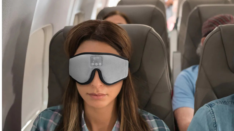 Woman on a plane wearing wireless sleep mask headphones