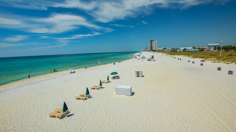 white sand beach with blue water and chairs and umbrellas set up