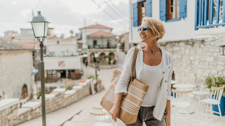 A single mature woman walking down a small town of Greece