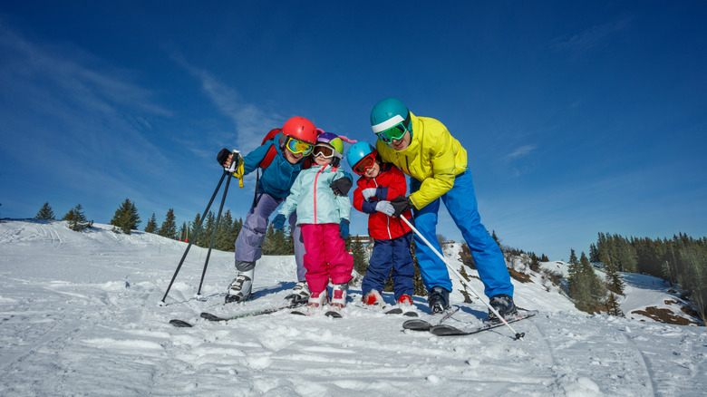 Family of four in ski gear pose together on a snowy slope