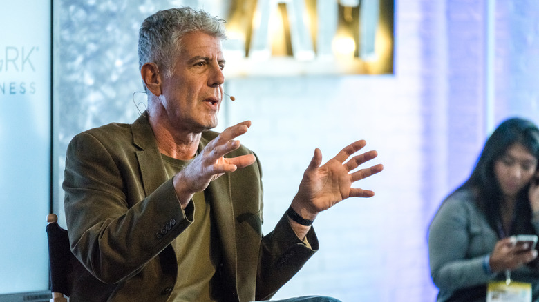Anthony Bourdain sits and gesticulates at a talk at SXSW in Austin