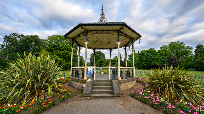 Bowie bandstand in Croydon Road Recreation ground surrounded by flowers, grass, and trees