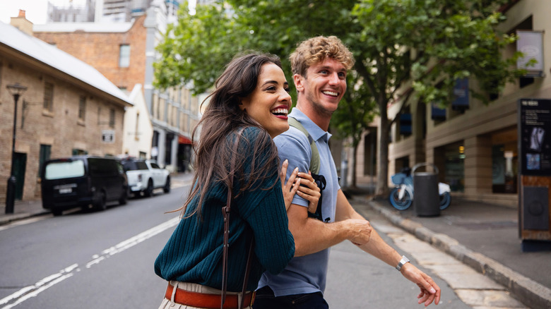 A young man and woman walk across and empty city street