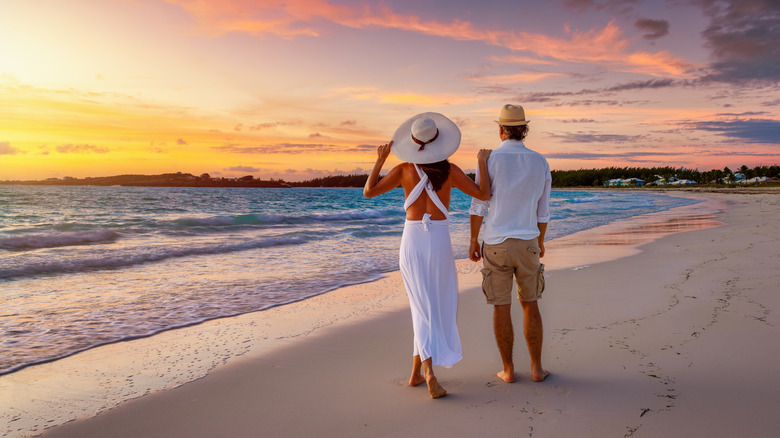A couple walking along the beach at sunset