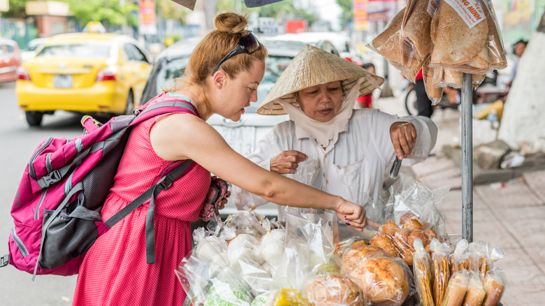 Western woman buying street food from Vietnamese vendor