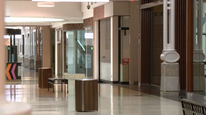 Empty hallway at Circle Center Mall, with gated storefronts along the right side of a white-tiled hallway with benches and trash cans