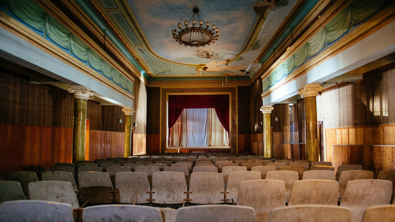Interior view of an abandoned theater with murals on the ceiling