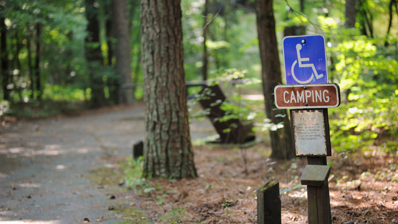 A campsite in the forest with a blue handicapped sign.