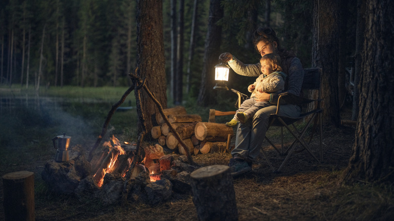 Mother and child with a camping lantern sitting by the fire