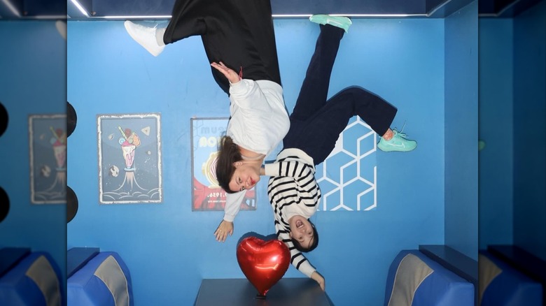 Two people appearing to hover upside down against gravity at the Museum of Illusions in Atlanta