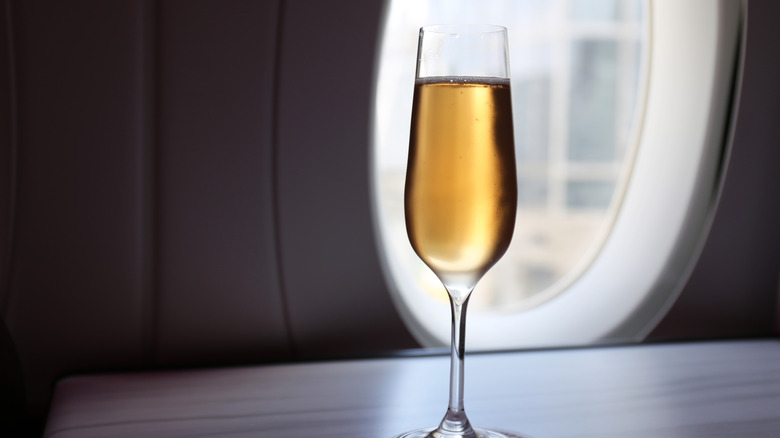A glass of champagne on the table of a seat in first class