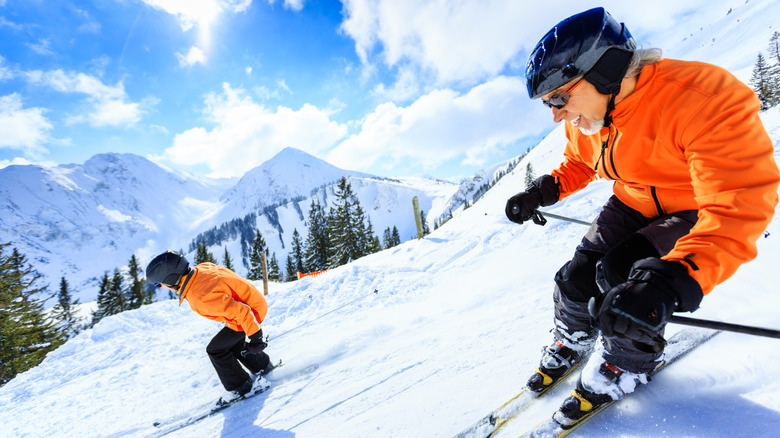 Senior couple skiing down a snowy mountain