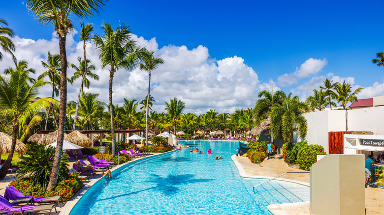 large resort pool with chairs and palm trees in Dominican Republic