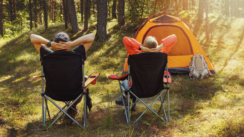 Couple relaxing in camping chairs by their tent