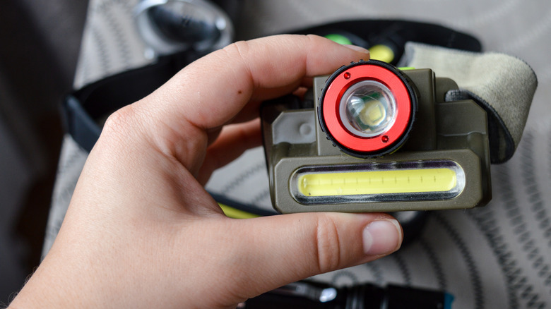 A hand holding an LED headlamp