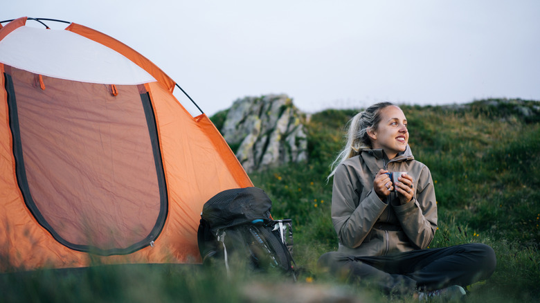 A person sitting outside their simple camping setup