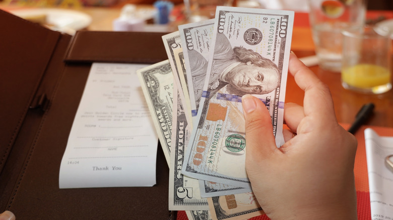 close-up on a person's hand with money for a tip at a restaurant