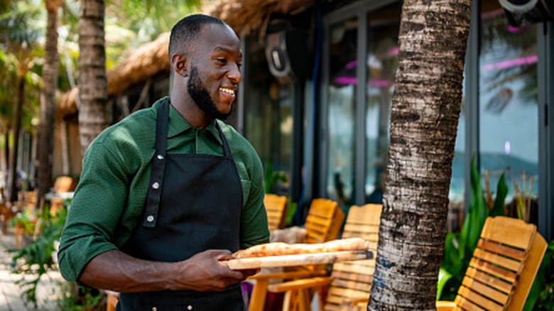 a friendly waiter serves food at a beachside cafe