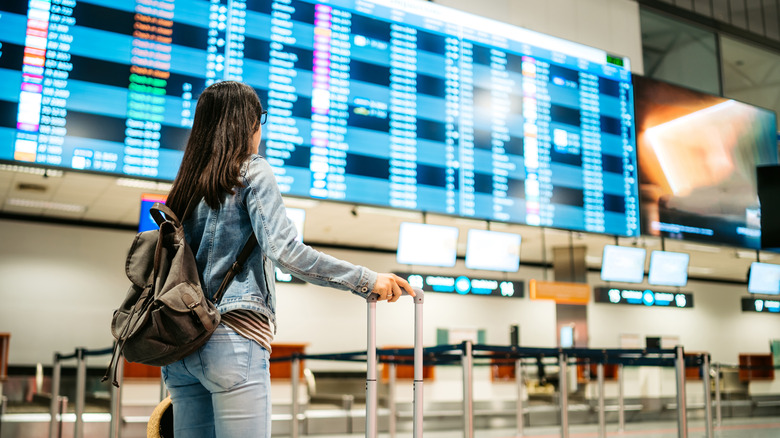 Woman stands in front of the arrivals board at Budapest International Airport
