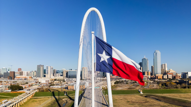 The Texas flag in front of the Margaret Hunt Hill Bridge in Dallas, Texas