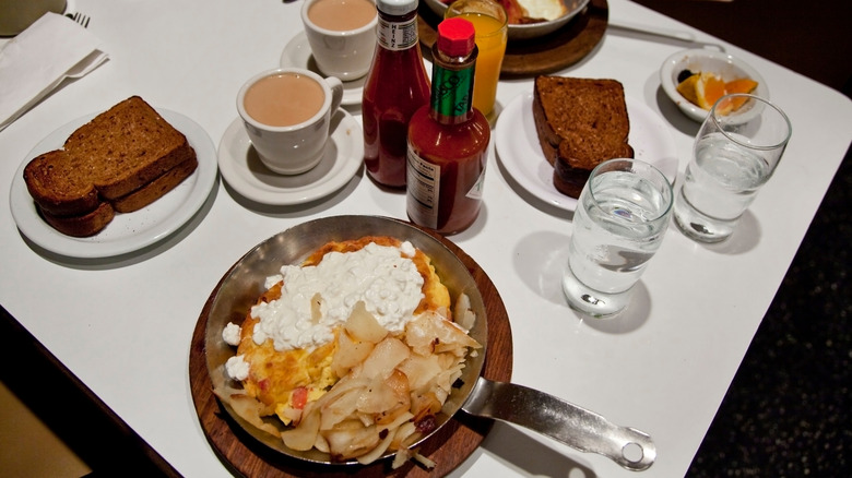 An overhead view of a diner breakfast with eggs, potatoes, bacon, and toast.