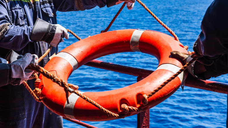 Someone throwing a buoy to a person who has fallen overboard
