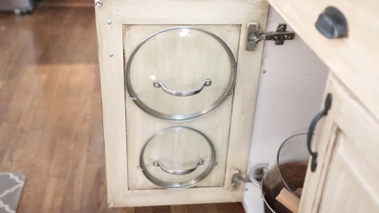 A cutting board hanging from a command hook on a cabinet door