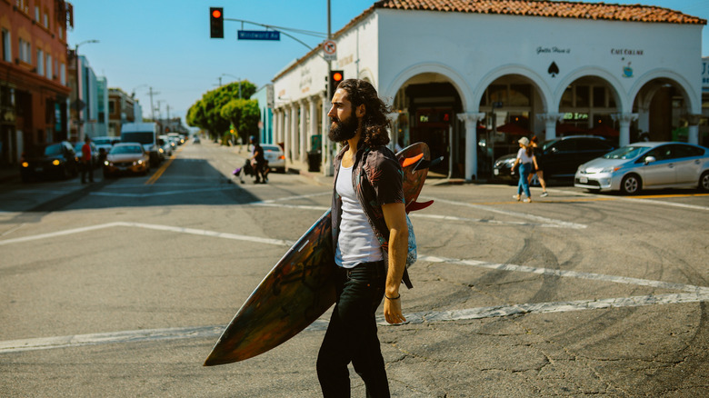 A person walks towards the ocean with a surfboard in California