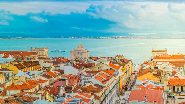 The colorful rooftops of Lisbon's old town with the ocean in the background