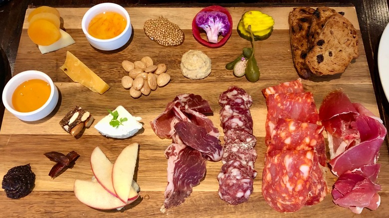 The cheese and charcuterie board at On Swann is an opulent spread including sides like almonds, pickles, and marmalades