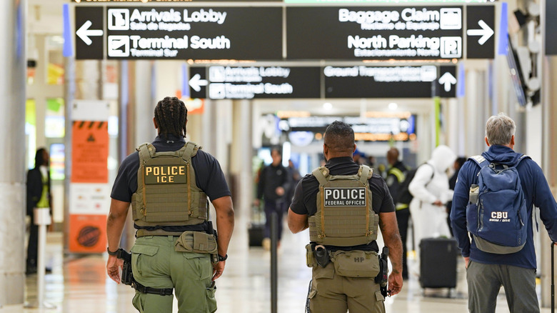 ICE agents from behind walk through airport