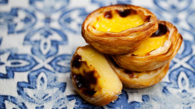 A pile of egg tarts on blue tiles in Portugal