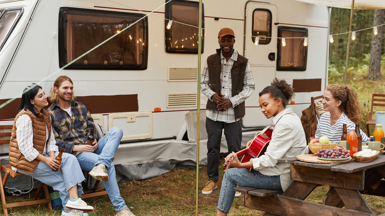 People enjoying a vacation sitting outside an RV