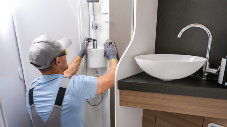 Someone installing a shower head in an RV