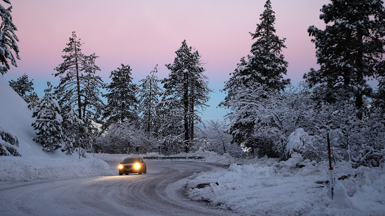 Car driving on a snowy road at sunrise in Wrightwood, California