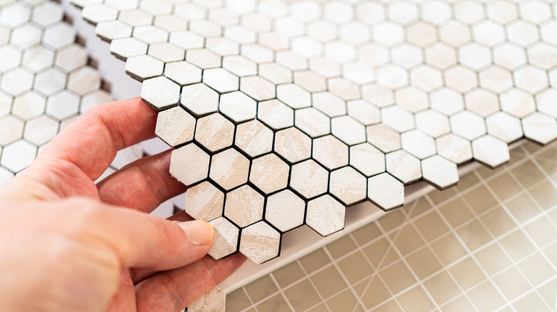 A hand measuring peel-and-stick hexagon tiles