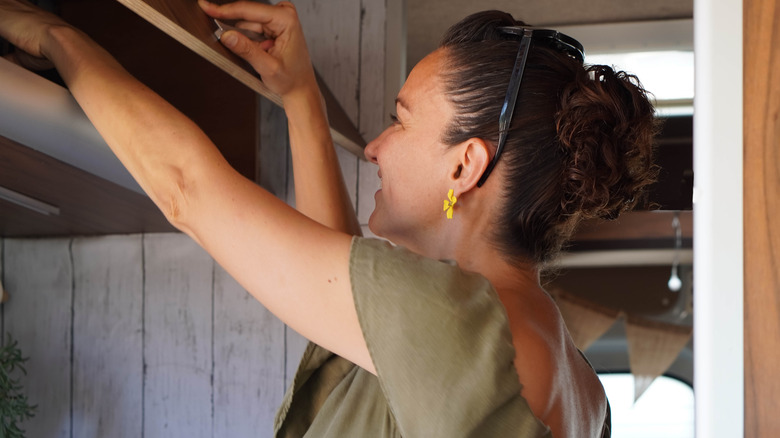 A woman opening a camper van cabinet